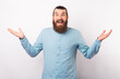 © Vulp - Wide smiling young bearded man shrugs over white background in a studio.