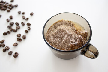 Poster - Closeup shot of coffee beans and a cup filled with coffeeon a white table