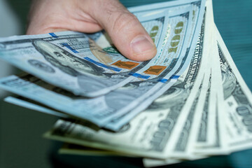 Wall Mural - Shallow focus shot of a person holding many hundred dollar bills