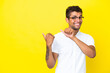 © luismolinero - Young handsome Brazilian man isolated on yellow background pointing to the side to present a product