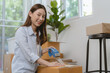 © KMPZZZ - Pretty, Smile owner business asian young woman holding packing, box by tape machine, sealing cardboard indoors. Business owner in warehouse, Moving or preparing in new house, apartment or relocation.