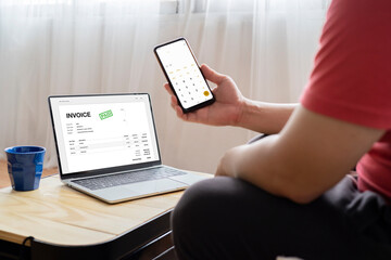 Close-up of a businessperson's hand analyzing invoice on laptop