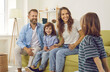 © Studio Romantic - Happy young mom and dad with kids at home. Cheerful European mother and father listening to their child sharing news of the day. Little son hides surprise he's prepared for his family behind his back