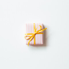 Wall Mural - Pink stripe pattern gift box with yellow ribbon isolated on white background. top view, copy space