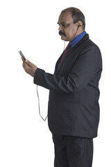 Wall Mural - Vertical shot of a man with a smartphone and headphones on a white background