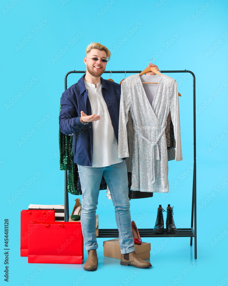 Male stylist with clothes on color background