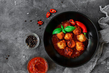 Wall Mural - Chicken meatballs with basil and tomato sauce. Dark background. Copyspace. Meatballs with tomato and chili. Top view