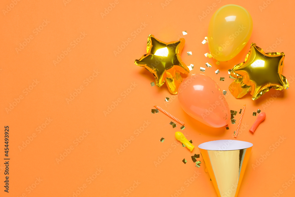 Party hat, balloons, candles and confetti on color background