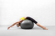 © junky_jess - Back stretching with fitness ball. Slim fit caucasian woman lying down on big exercise ball and extend her spine in loft studio indoor.