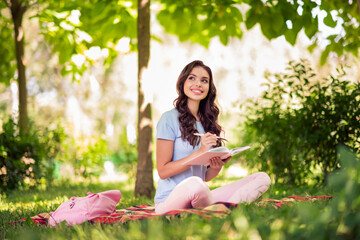 Wall Mural - Full length body size photo woman writing in diary sitting on plaid blanket in city park