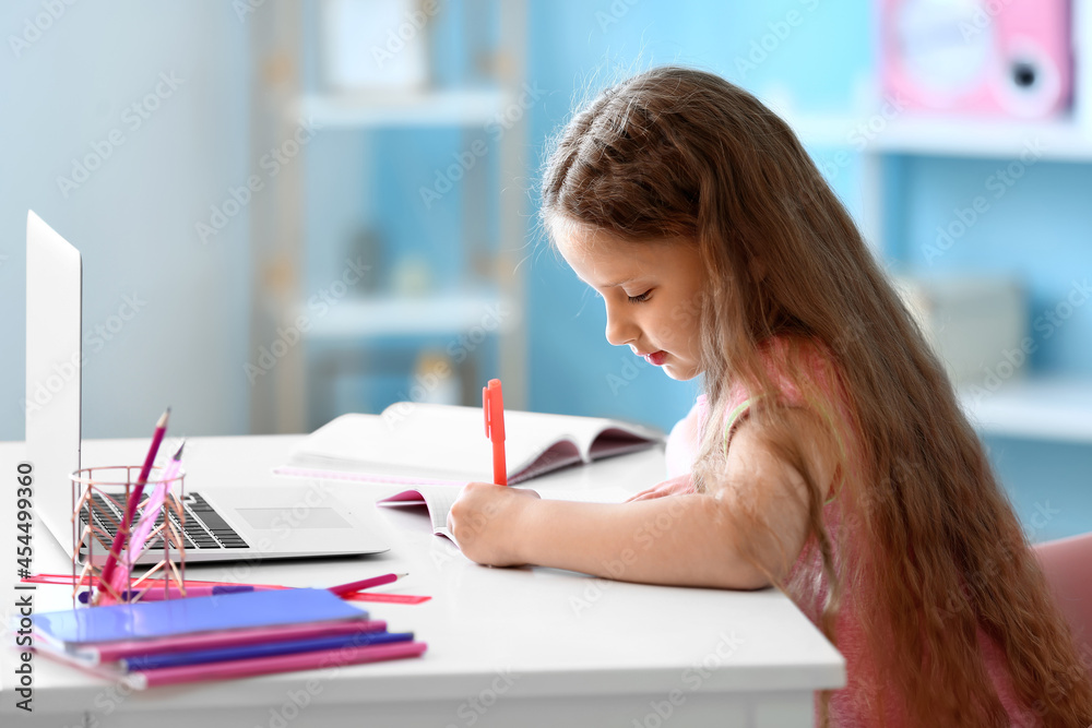 Little girl writing in notebook at home