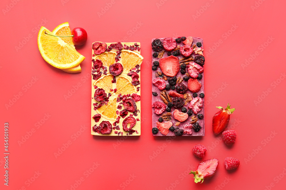 Handmade chocolate bars with fruits, berries and nuts on color background