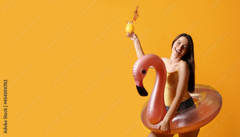 Young woman with cocktail and inflatable ring on color background