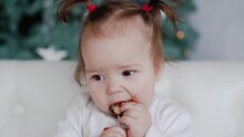 Close-up 4k Video Portrait Of Cute Funny Thoughtful Little Baby Girl Eating Chocolate Candy In Holiday Christmas Interior