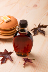 Wall Mural - Beautiful Canadian maple syrup in a bottle on a light wooden background. Pancakes with syrup or honey.
