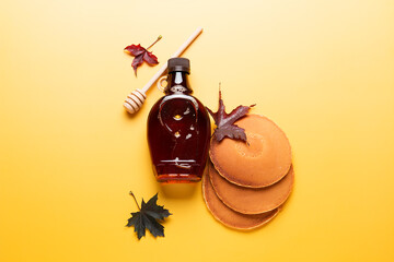 Wall Mural - Maple syrup on yellow background. Pancakes with maple syrup or honey. Traditional breakfast.
