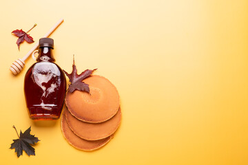 Wall Mural - Maple syrup on yellow background. Pancakes with maple syrup or honey. Traditional breakfast.
