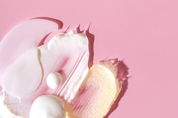 Various cosmetic mask, creams, serum, scrub and lotion smear on a pink background. Beauty texture. Sample of a cosmetic product.