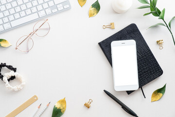 Fototapete - Feminine desk table with mobile phone mockup, notebook, keyboard, office supplies on white background. Flat lay, top view. Elegant workspace.