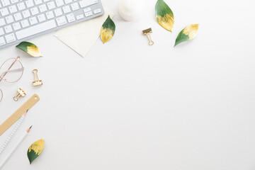 Fototapete - Feminine desk table with keyboard, green leaves, office supplies on white background. Flat lay, top view, copy space.