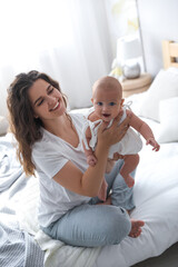 Canvas Print - Happy young mother with her cute baby on bed at home