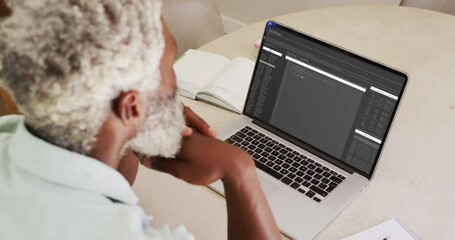 Wall Mural - African american man sitting at desk watching coding data processing on laptop screen