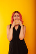 © Marina Chernivetskay - a girl with pink hair of European appearance looks at the burger biting her tongue licking wants to eat it