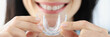 © H_Ko - Woman holding plastic mouth guard for bruxism treatment closeup
