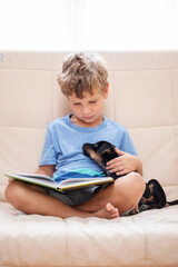 Wall Mural - A boy with a little dog is reading a book