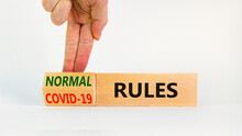 Symbol Of Covid-19 Or Normal Rules. Doctor Turns A Wooden Cube And Changes Words 'covid-19 Rules' To 'normal Rules'. Beautiful White Background, Copy Space. Medical, Covid-19 Or Normal Rules Concept.