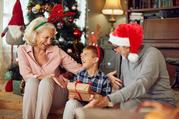 Wall Mural - Joyful boy receives  present from grandparents on Christmas at home.