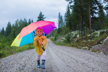 Canvas Print - Cute toddler child with colorful umbrella, playing in the forest on a rainy day