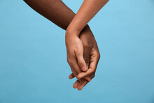 Woman And African American Man Holding Hands On Light Blue Background, Closeup