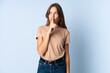 © luismolinero - Young Lithuanian woman isolated on blue background showing a sign of silence gesture putting finger in mouth