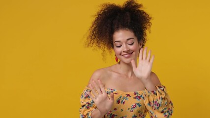 Canvas Print - Vivid happy young latin curly woman 20s wears casual flower dress dance clenching fists waving rising expressive gesticulating hands fooling around have fun enjoy isolated on plain yellow background