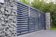Gabion. Automatic entrance gate used in combination with a wall made of gabion.
