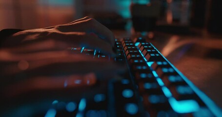 close up hands typing on keyboard programmer coding software gamer using keyboard with blue backlight playing game at night