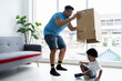 Happy African American family. Cheerful father and little son playing hide and seek with parcel box together in living room at home. Family and holiday concept