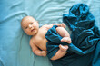 Adorable boy in the bedroom. A newborn baby is resting in a blue-colored bed. Textiles and bedding for children. Family morning at home. Selective focus.