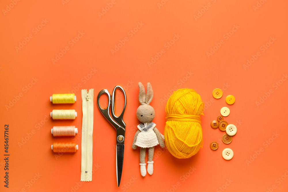 Composition with knitting supplies and toy on color background