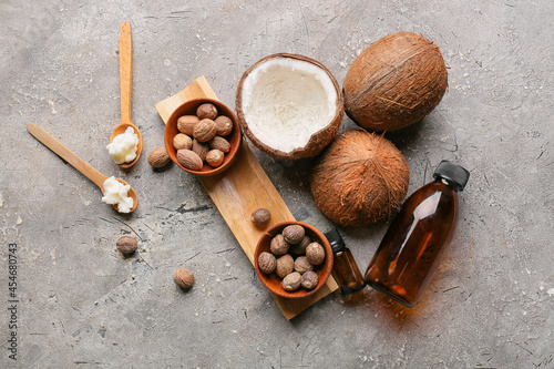 Composition with shea butter, nuts, bottles of essential oil and coconuts on grunge background