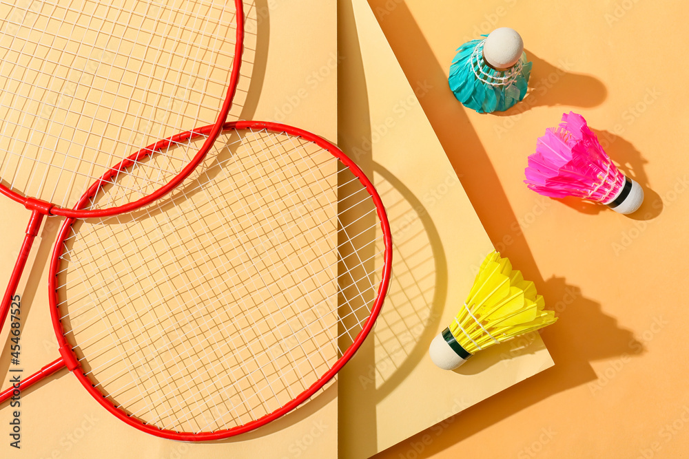 Badminton rackets and shuttlecocks on color background