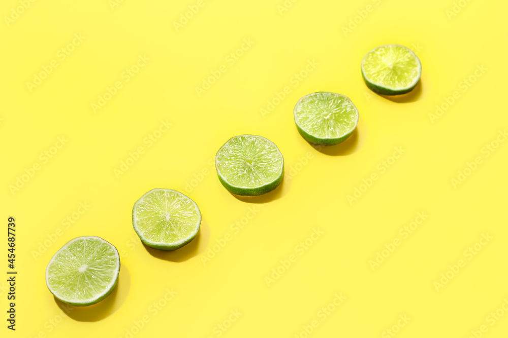 Tasty lime slices on color background
