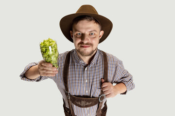 Wall Mural - Happy smiling man dressed in traditional Bavarian costume holding beer glasses filled with wild hot and barley. Celebration, oktoberfest, festival concept.