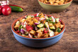 Italian vegetarian panzanella salad in a clay bowl on a table with ingredients - rustic style