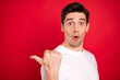 Photo of funky brunet millennial guy point empty space wear white shirt isolated on red color background