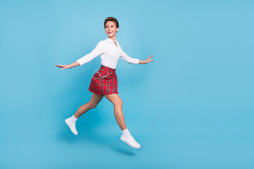 Poster - Full body profile photo of funky blond young lady jump look empty space wear shirt skirt sneakers isolated on blue background