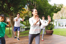 Happy Asian Parents, Son And Daughter Exercising Outdoors, Practicing Tai Chi