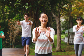 Wall Mural - Happy asian parents, son and daughter exercising outdoors, practicing tai chi