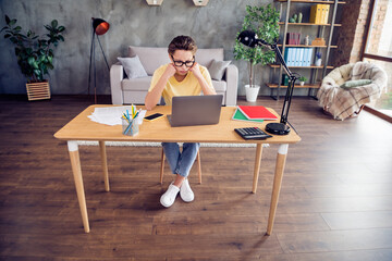 Poster - Photo of tired upset young lady wear yellow t-shirt sitting table arms cheekbones working modern gadget indoors room home